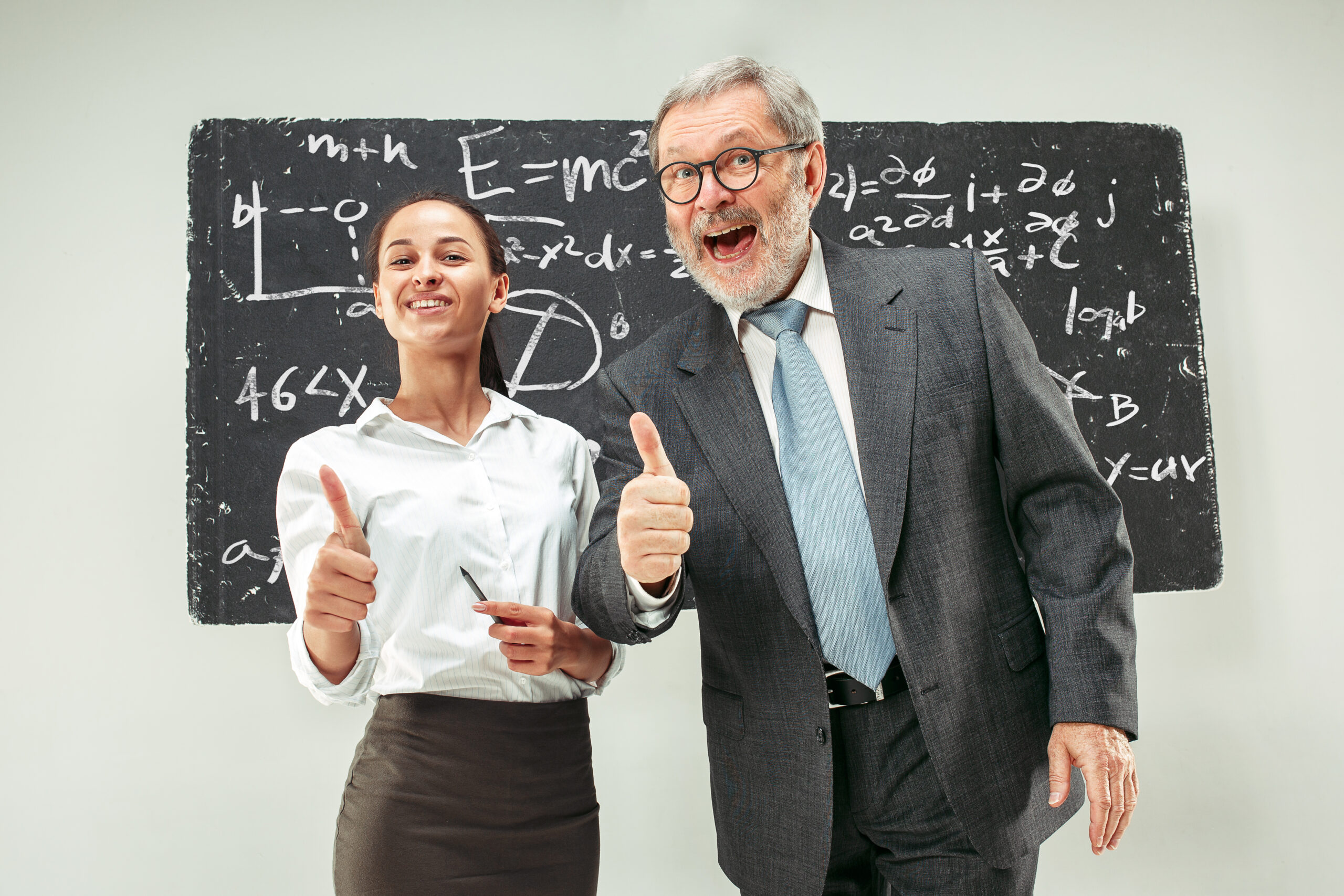 Male professor and young woman against chalkboard in classroom